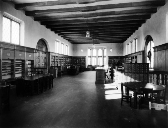 Interior view of the Park Hill Branch of the Denver Public Library in Denver, Colorado; decor includes tables, chairs, card catalogs, arched windows, and open-beamed ceilings.