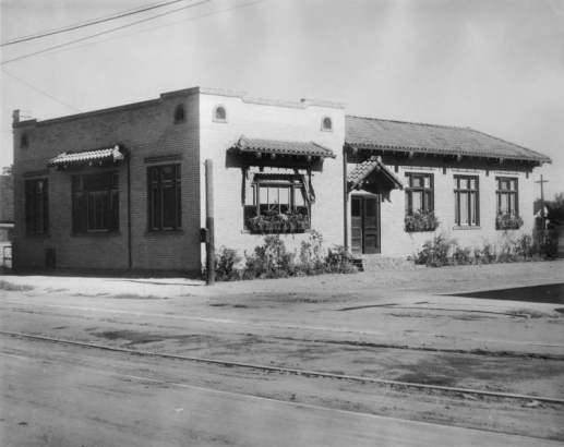 View of the Globeville Branch of the Denver Public Library at 4496 Grant Street in the Globeville neighborhood of Denver, Colorado; features a tile roof and awnings. Streetcar tracks are in the foreground.