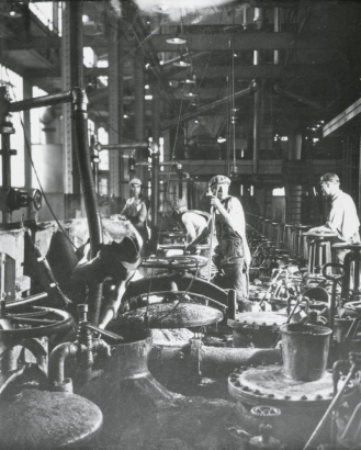 Interior view of a Great Western Sugar processing facility in Colorado; men work by vats and pipes.