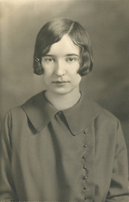 Evelyn Tunstall poses for her South High School senior portrait in Denver, Colorado. Tunstall's hair is styled in a bob with a barrette clip and she wears a frock with a rounded collar and a row of pearl buttons on the side.