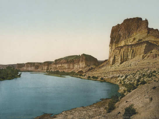 View of eroded striated bluffs and cliffs, the pillar Tollgate Rock and The Palisades on Green River in Sweetwater County, Wyoming.