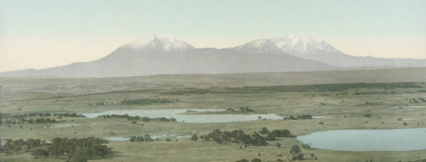 Panoramic view of unidentified lakes or ponds, a plain scattered with trees, and the Spanish Peaks in Huerfano County, Colorado.