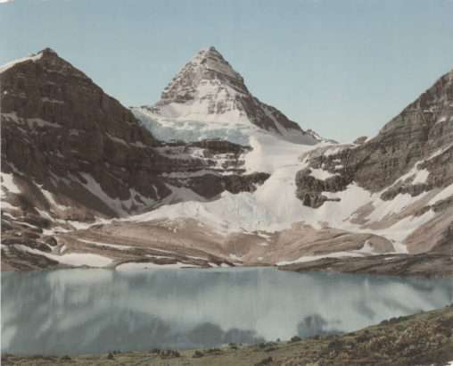 View of Lake Magog, a glacier, and Mount Assiniboine in Mount Assiniboine Provincial Park in British Columbia, Canada.  Shows an alpine lake at the foot of rugged snow covered peaks.