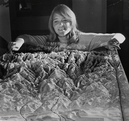 Miss Brigitte Bastian, sports secretary to the Denver Olympic Committee, surveys a scale model of Denver and surrounding mountains to be used in the city's bid for the 1976 Winter Olympic Games. Denver will make its presentation May 12 in Amsterdam.