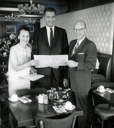 Part of the success of Denver-based Village Inn Pancake Houses lies in their menus. Mrs. Roma Brown looks over the menu with her brother-in-law Merton Anderson, center, secretary-treasurer, and brother, James P. Mola, president. 
