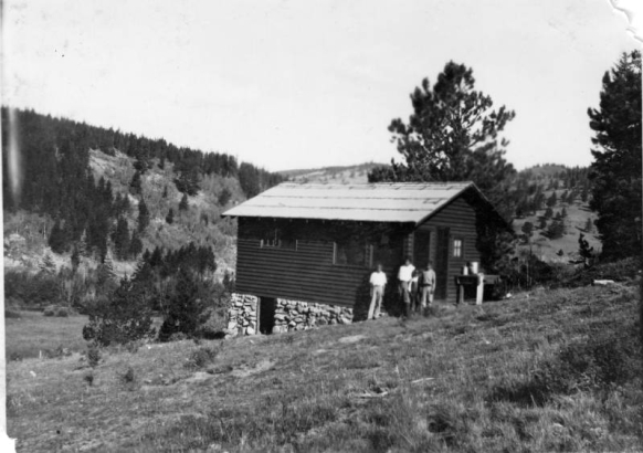View of Pitts Cabin and group of four individuals in Lincoln Hills (Gilpin County).
