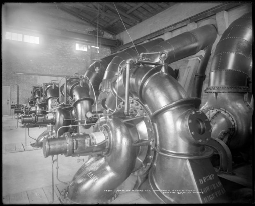 Interior view of Orchard Mesa ditch power plant, Mesa County, Colorado; shows four large turbine pumps, brick building, and pressure gauge.