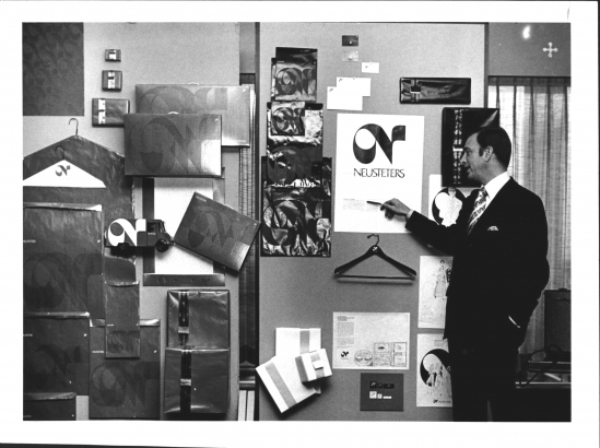 A pain stands and points to a variety of logos and packaging on a wall