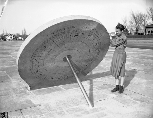 Young girl stands next to sundial in Hilltop Neighborhood's Cranmer Park, March 1941