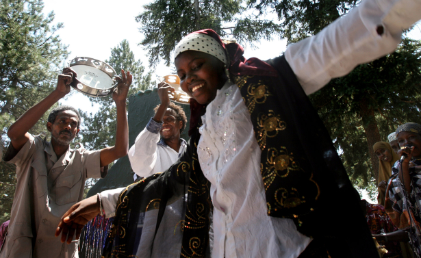 16 year-old Sahra Bashir (cq) from Somalia dances to some East African Music, as fellow Somalians, 47 year-old Bare Munye (cq) (at left) and 24 year-old Bashir Ararso (cq) from the Sabaree Africa Cultural Organization (at center), make some sound at Washi