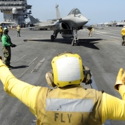 Aircraft carrier USS Theodore Roosevelt (CVN 71) deck crew guides a fighter jet, 