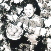 Lotus Room hostess Ruth Jung celebrates Chinese New Year with traditional offering of oranges and gold coins. 1961