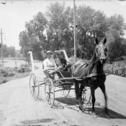 Men pose in a horse-drawn buggy on Alameda Avenue in Denver, Colorado. Shows the bridge over Archer Canal.