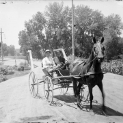 Men pose in a horse-drawn buggy on Alameda Avenue in Denver, Colorado. Shows the bridge over Archer Canal.