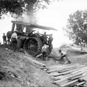 View of men driving a steam tractor up an embankment, in Denver, Colorado.