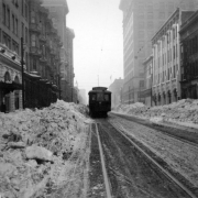 A street car makes its way along 17th (Seventeenth) Avenue, Denver, Colorado. Snow has been cleared and piled high on sides of streets. Landmark buildings include the Albany Hotel and the 1892 Equitable Building.