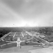 View west from dome of State Capitol Building over Civic Center, Denver, Colorado, shows the cruciform plan located between West Fourteenth Avenue and West Colfax. Landmarks include: Pioneer Monument, the Andrew Carnegie funded 1909 Denver Public Library, United States Mint, Arapahoe County Courthouse and the Daniels and Fisher Tower. Signs read: "Boss Rubber Co.," "Goodyear Tire & Rubber," "The Manualo," "The Baldwin Piano Co." and "Thurney Auto Co." Snowcovered Front Range shows in background.