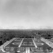 View west from dome of State Capitol Building over Civic Center, Denver, Colorado, shows the cruciform plan located between West Fourteenth (14th) Avenue and West Colfax. The Denver Public Library and the United States Mint show prominently among buildings that later would be raised for Civic Center exspansion. Signs on Cleveland Place read: "The Manualo," "The Baldwin Piano Co." and "Thurney Auto Co."