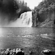 Upper Falls of the Yellowstone River, Yellowstone National Park, Wyoming, shows the raging waterfall with a wooden stairway on a rocky cliff leading to a vantage point.
