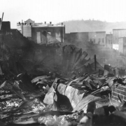 Destruction caused by second fire, April 29, 1896, Cripple Creek,  Colorado; shows rubble, debris, twisted sheet metal, brick foundation, two-story wood and brick commercial buildings with false fronts in background.