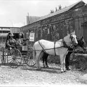 Men pose in a horse drawn buggy in Rifle (Garfield County), Colorado; one holds a handbill: "Denver The Great Western Livestock Market - The Denver Union Stock Yards - Home Market." Sign reads: "Winchester Hotel."
