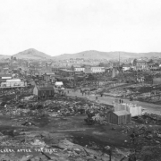 View west across building remains from first fire on April 25, 1896 fire, Cripple Creek, Colorado; many commercial buildings still remain in business district; evidence of construction of new wooden framed buildings is in the foreground; Mt. Pisgah is on distant horizon.