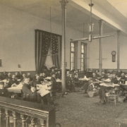 Senators, who include Senator Casimiro Barela (right rear), pose in the Colorado State Assembly Senate Chamber in Denver, Colorado. Show men at their desks, boy pages and probably the President of the Senate who sits at an elevated desk.