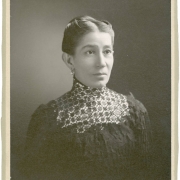 Studio portrait of Damiana Rivera de Barela. wife of Colorado State Senator Casimiro Barela. She wears a black lace dress with a high neck, pearl earrings and her hair pulled back and waved.