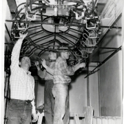 Photograph of three unidentified men during a class in ceiling construction at the Emily Griffith Opportunity School located in Denver, Colorado.  The three men stand on platforms and are working on the curved oval structure.