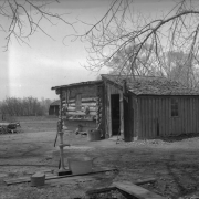 Old Olsen's log and plank shack residence Petersburg (later Englewood), Arapahoe County, Colorado, includes a hand pump and washtub.