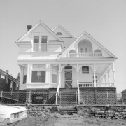 Exterior view of Charles N. and Josephine Miller's former residence, 127 West Carr, Cripple Creek, Colorado; This two-story Queen Anne style residence built in 1897 or 1898 has pitched roof porch with balustrades, and recessed and encircling porch; other characteristics include multi-gabled or triple gabled roof line, bay windows, tall stone foundation, bargeboard, scalloped shingling, and wire fence with gate around perimeter of yard.