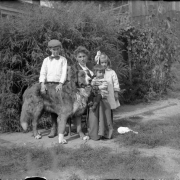 Outdoor portrait of a woman, her sons, daughter, and dog in a garden in Denver, Colorado. The girl wears a ribbon in her hair and one son wears a bow tie and cap.
