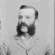 Studio portrait of a man (bust), he wears a jacket, vest and necktie. The man has muttonchops and a moustache (Franz Joseph style).