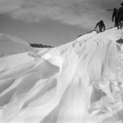 Members of the AdAmAn Club climb among rocks and snow, above Colorado Springs, El Paso County, Colorado. Contoured banks and drifts of snow are in the foreground.