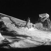 Night view taken during the AdAmAn Club's annual New Year's Eve climb of the upper terminal of the Pikes Peak Cog Railway encrusted with ice, above Colorado Springs, El Paso County, Colorado. Teeth of the railway show through the snow and footprints lead to the platform.