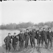 Outdoor portrait of a group of men near the South Platte River in Denver, Colorado. Some of the men wear baseball uniforms that read: "[?]land".
