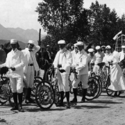 Sunflower Carnival Parade entrants pose in white outfits with white duster or conductor hats, Colorado Springs, El Paso County, Colorado.  Their bicycles are adorned with flowers and bunting.