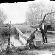 Portrait of a man with a Newfoundland dog by Archer Canal and the South Platte River bridge in Denver, Colorado.