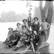 Outdoor portrait of a group of girls dressed as men and a man near the South Platte River in Denver, Colorado. The girls wear wide brimmed hats and hold pipes and cigarettes.