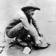 View of miner panning for gold in placer mining district of (possibly) Clear Creek west of Denver, Colorado