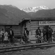 View of the Log Cabin, one of the first buildings built in Colorado Springs, El Paso County, Colorado. Governor Hunt built This cabin, when the Denver and Rio Grande railway arrived, in October 1871, it became the station restaurant. Identified figures, extreme left to right are: Governor Hunt, Mrs. Elisabeth Hunt McDowell (Hunt's daughter) Ed Eaton, Mrs. Helen McDowell Malhern, Major John H. McDowell (Hunt's son-in-law.) The McDowell's ran the restaurant.