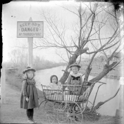 Outdoor portrait of three children near the edge of Archer Canal in Denver, Colorado. A nearby sign reads: "Keep Out Danger No Thoroughfare".