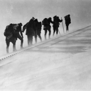 Snow blows by seven members of the AdAmAn Club as they make their way up a steep incline of the Pikes Peak Cog Railway tracks on Pikes Pike, an annual mountaineering trek to the top of the 14,110 foot mountain to set off fireworks on New Years Eve, Colorado Springs, El Paso County, Colorado. They carry backpacks, walking sticks and a camera tripod.