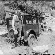 A man stands near his automobile that is stuck in a creek in Colorado.