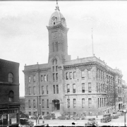 A view of the old City Hall located at 14th (Fourteenth) and Larimer Streets in Denver, Colorado. Shows a three story building with a clock tower, it was built in 1886 and demolished in 1936.