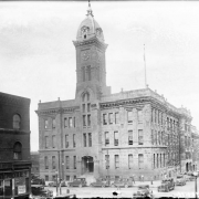A view of the old City Hall located at 14th (Fourteenth) and Larimer Streets in Denver, Colorado. Shows a three story building with a clock tower, it was built in 1886 and demolished in 1936.