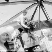 Mrs. Carlos L. Reavis of Denver hands a bouquet of flowers to Amelia Earhart, on Earhart's arrival in a Beech Nut autogiro, Denver, Colorado. Five other women stand nearby.