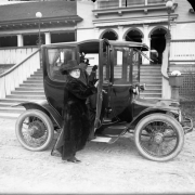 View of Addie Mellon and Harry Fisher Rhoads, parents of Harry M. Rhoads, with an electric automobile in front of City Park pavilion, Denver, Colorado.