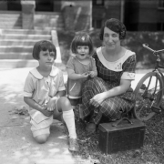 Mrs. Harry M. (Sade) Rhoads, and her daughters Mary Elizabeth and Harriet, pose with a tricycle outside the family home at 642 Logan Street, Denver, Colorado.