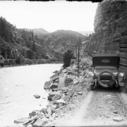 View of a car on the Taylor State Road, in Glenwood Canyon (Eagle or Garfield County) Colorado; Denver and Rio Grande Railroad tracks are across the Colorado River.